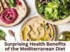 Evidence-Based Benefits of the Mediterranean Diet Overhead view of Mediterranean foods with hummus, beet dip, pita, and salad. Text overlay reads: Surprising Health Benefits of the Mediterranean Diet.
